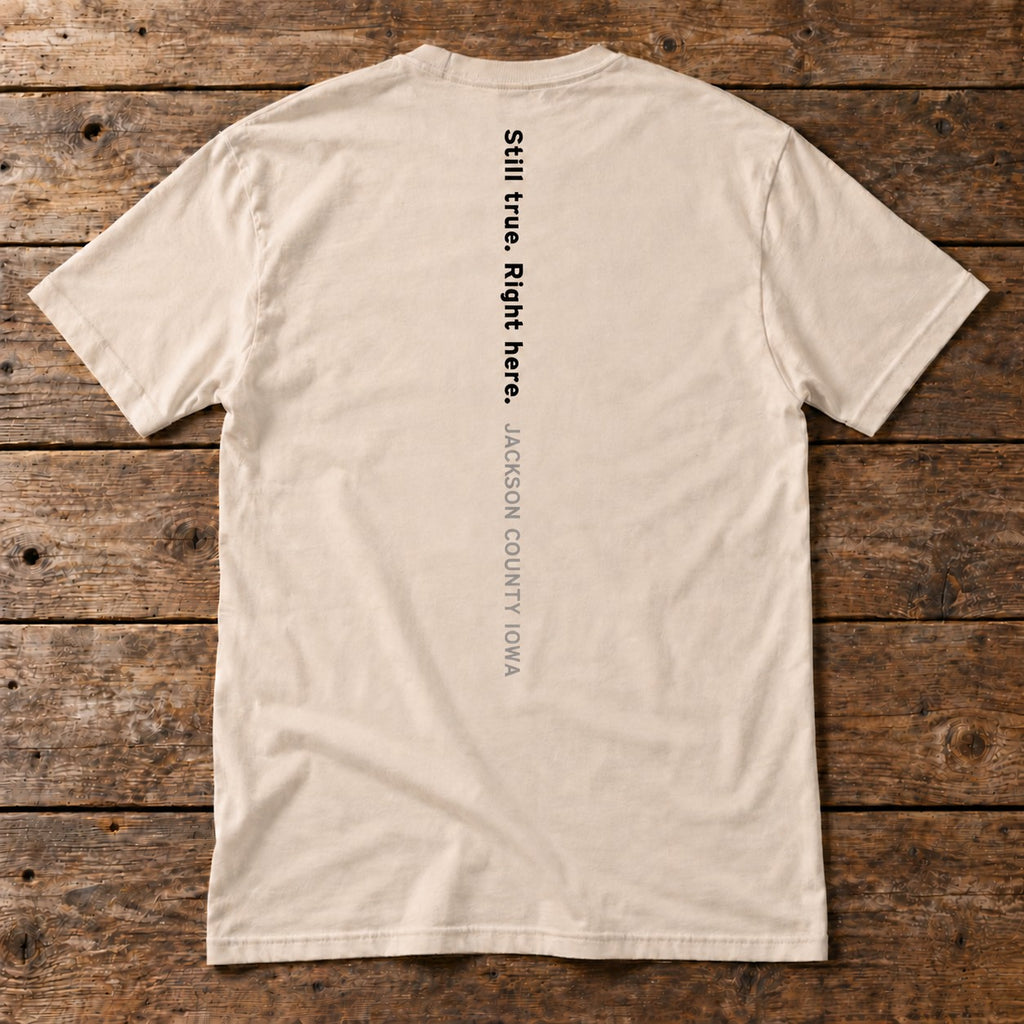 Back of the A Place to Grow Tee reading Still true. Right here. Jackson County Iowa